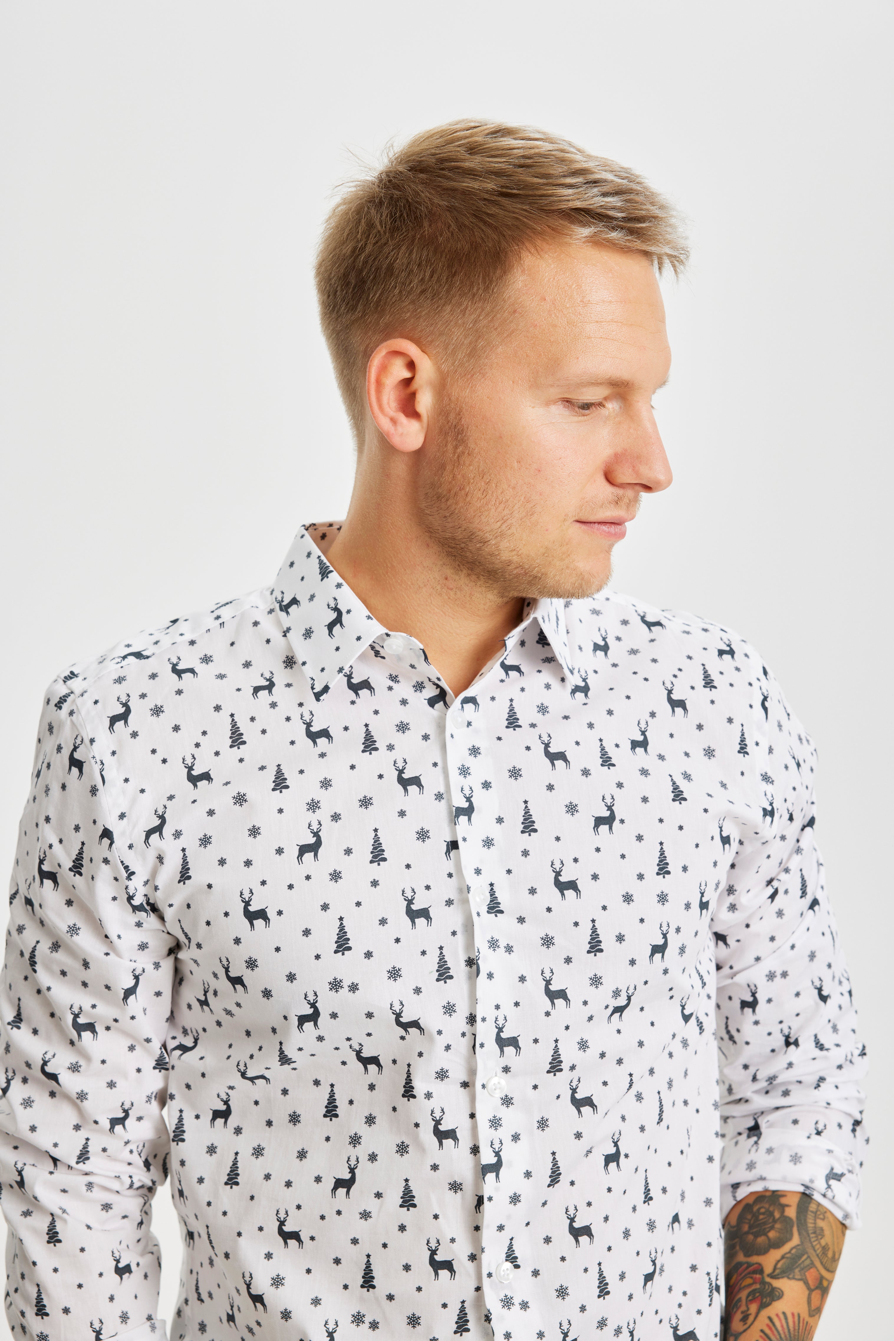 Un homme posant avec une chemise de Noël blanche imprimée.